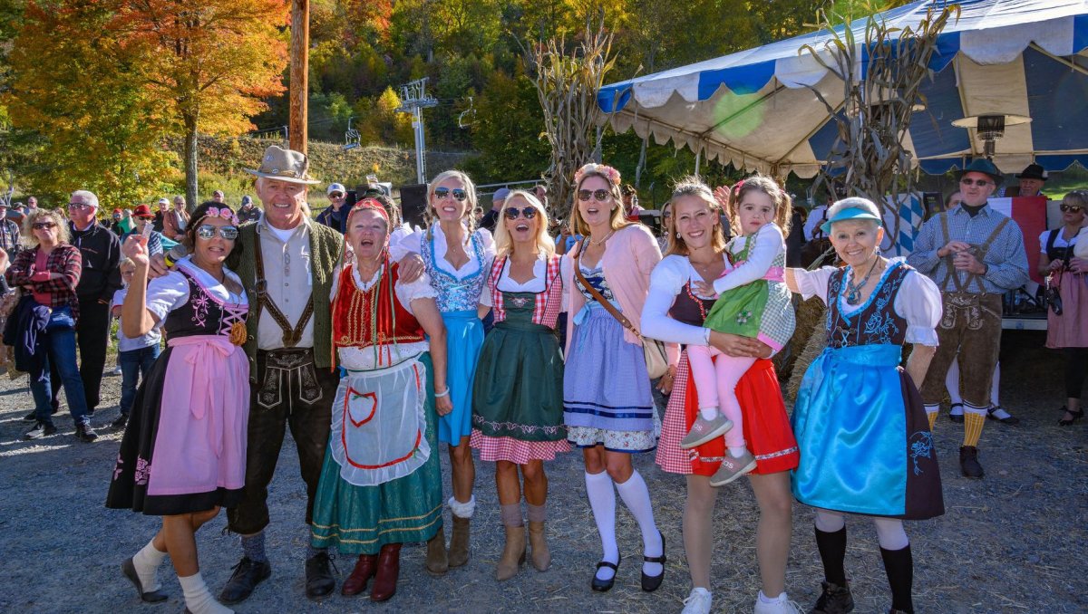 Family dressed in Bavarian clothing smiling for camera at Oktoberfest celebration