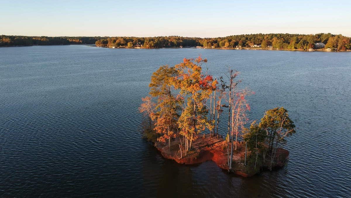 Aerial view of island in Lake Norman and shore in background with fall foliage 