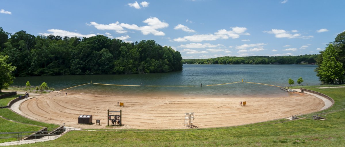 Empty sand beach with lake, trees and shoreline in front of beach