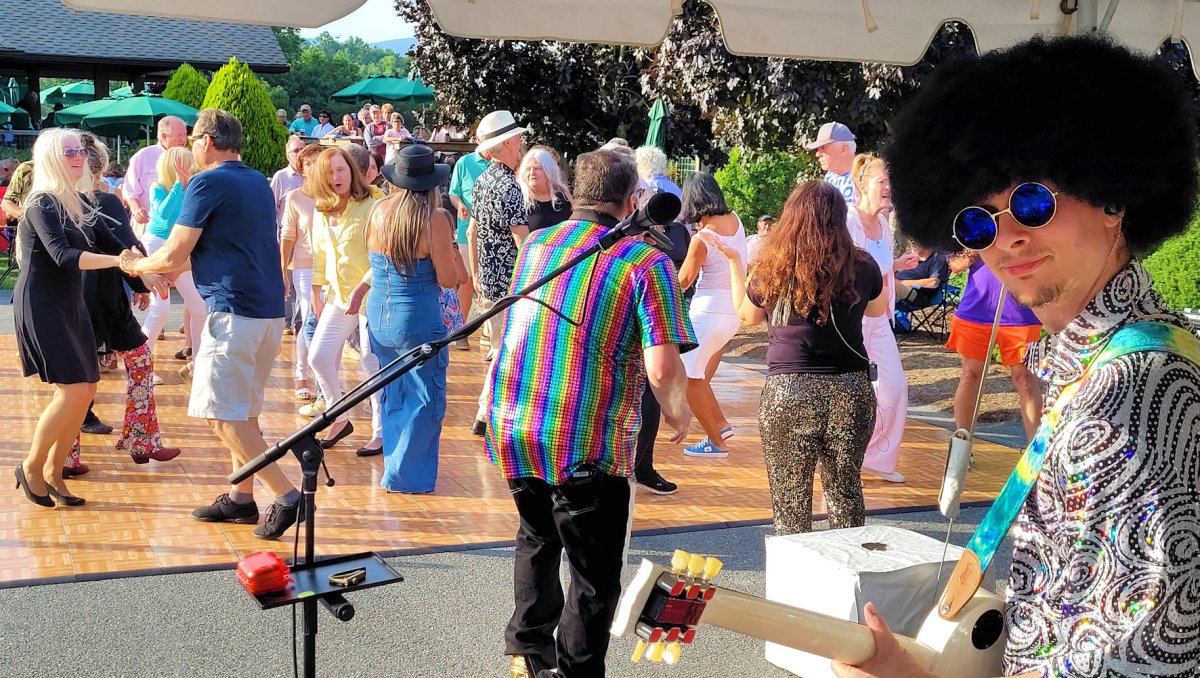 Musician playing guitar as locals dance in background
