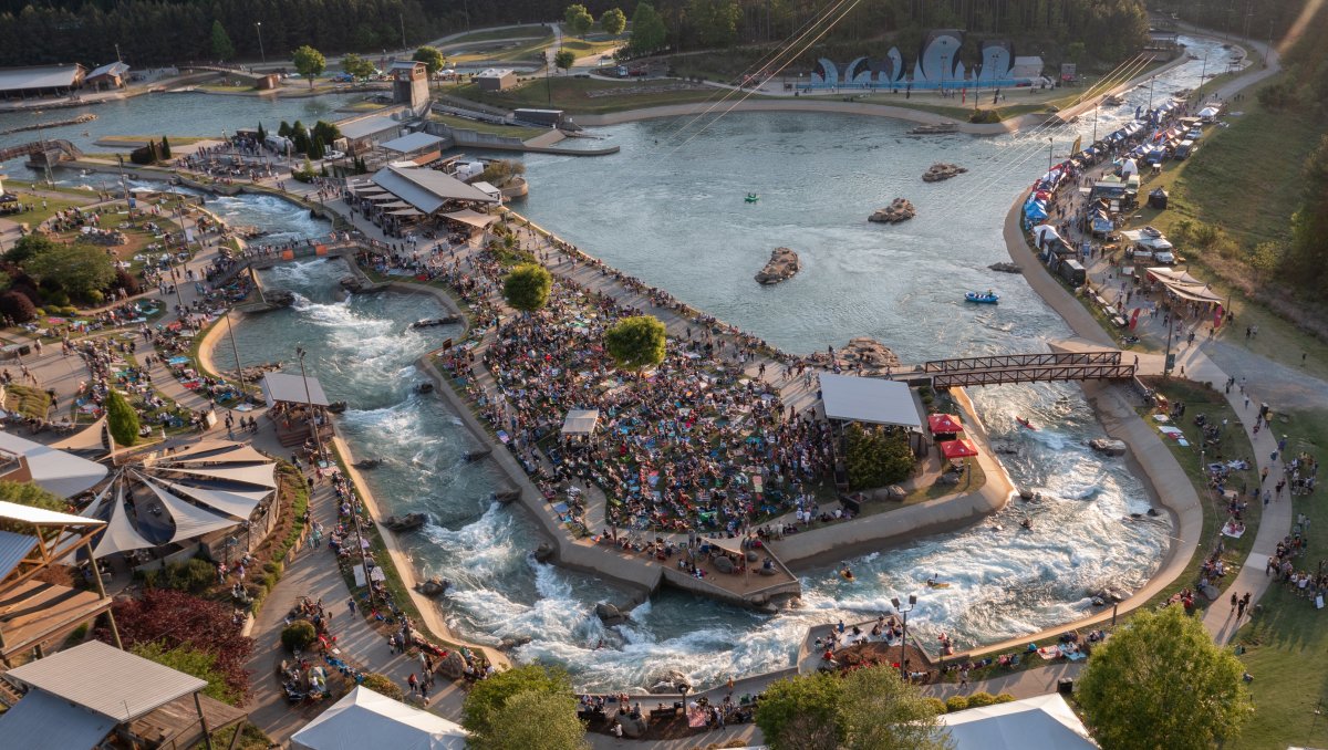 Aerial shot of outdoor whitewater center with tons of people on lawn during daytime