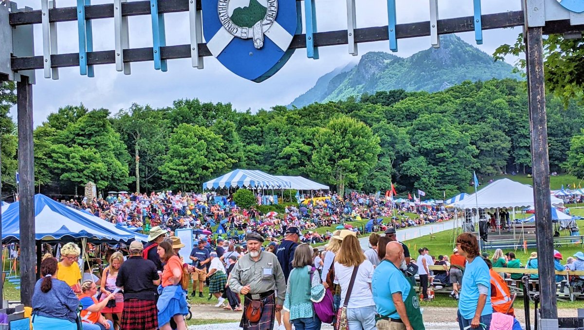 Entry to Highland Games event with large crowds and mountains in background