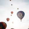 Many colorful hot air balloons in sky during gray day