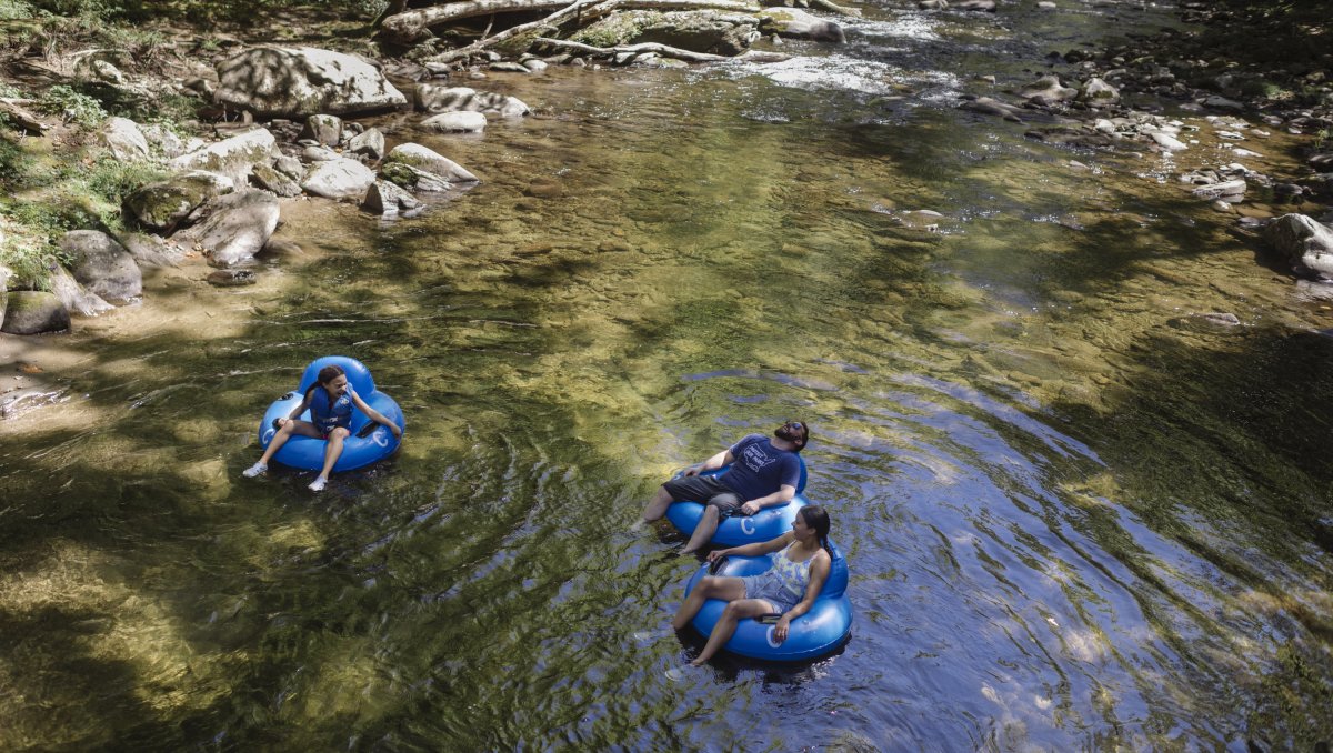 Aerial of father and two kids in blue intertubes on river in mountains