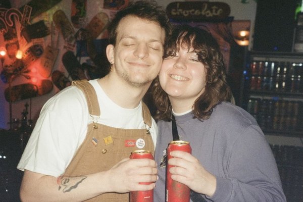 Couple smiling while holding red drink cans