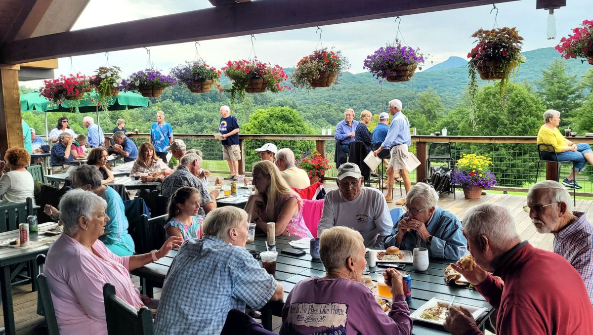 Diners enjoying meals on patio outside with mountains in distance