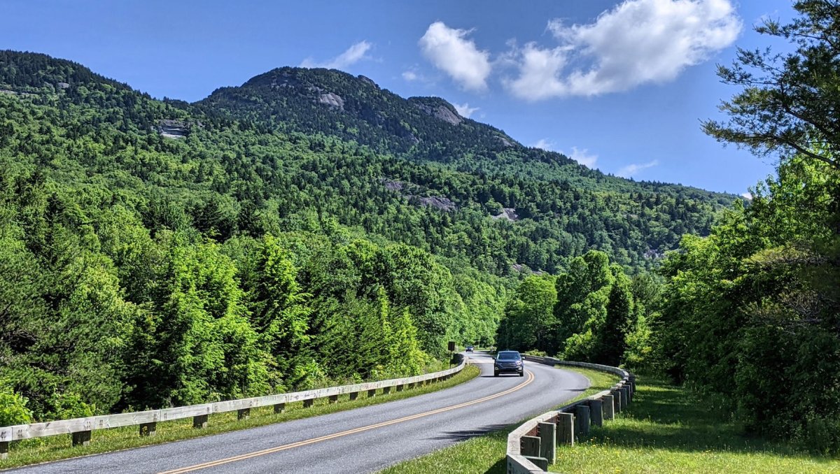 Car driving on Blue Ridge Parkway with trees and mountains in background