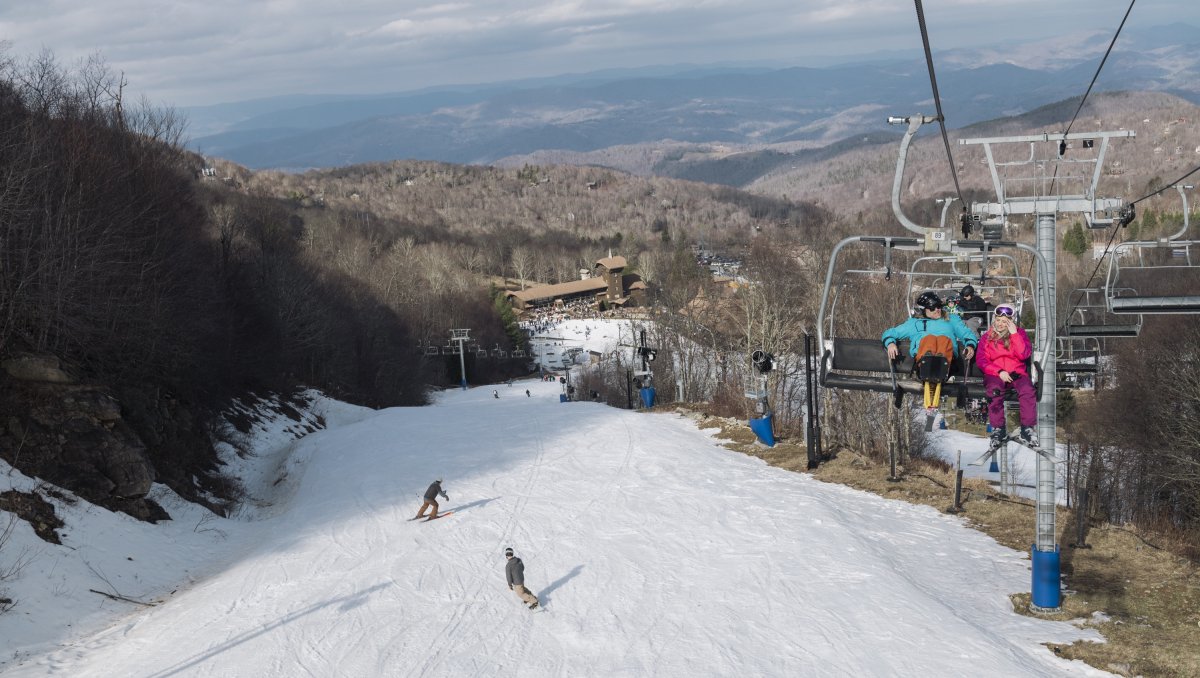 Aerial of people snowboarding down mountain and ski lift to the right