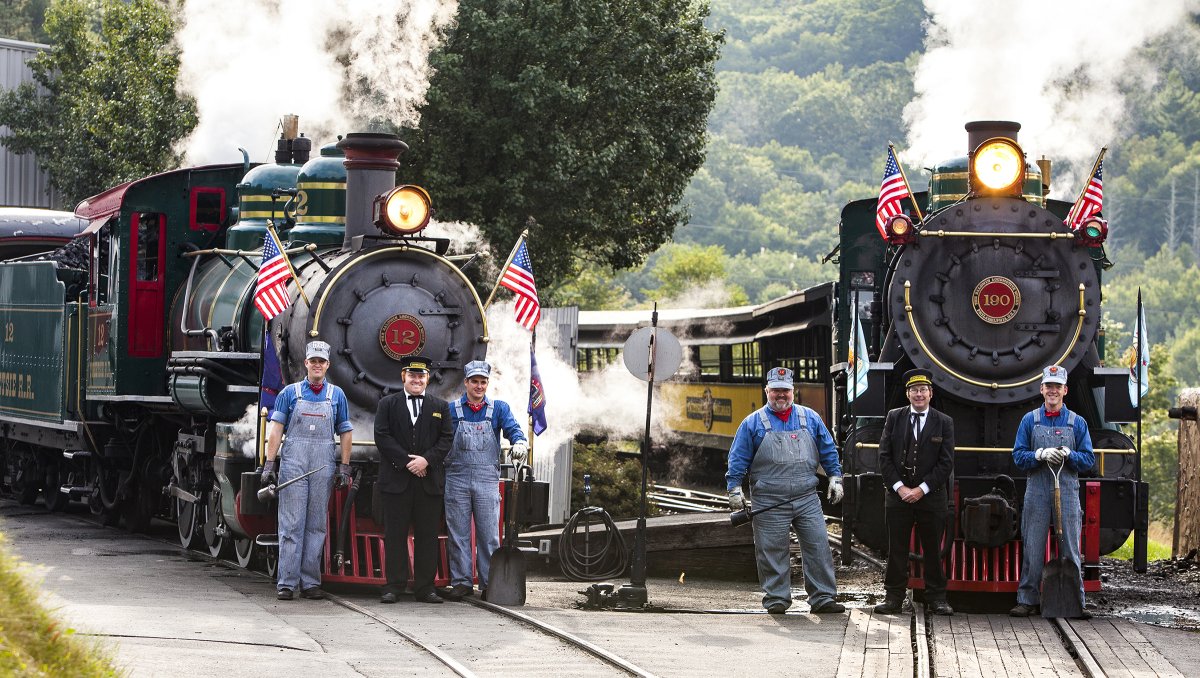 Tweetsie Railroad train workers standing in front of two steam-powered trains