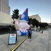 Woman standing in front of inflatable gnome on sidewalk