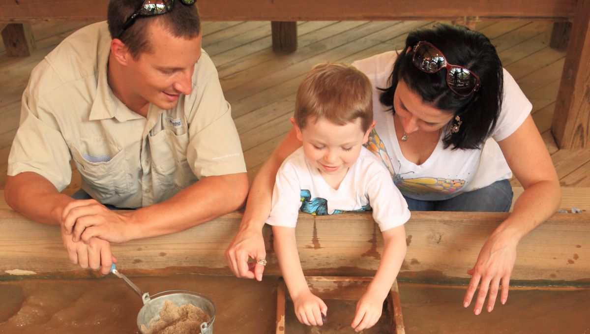 Mom, dad and young son sift through dirt to find gems
