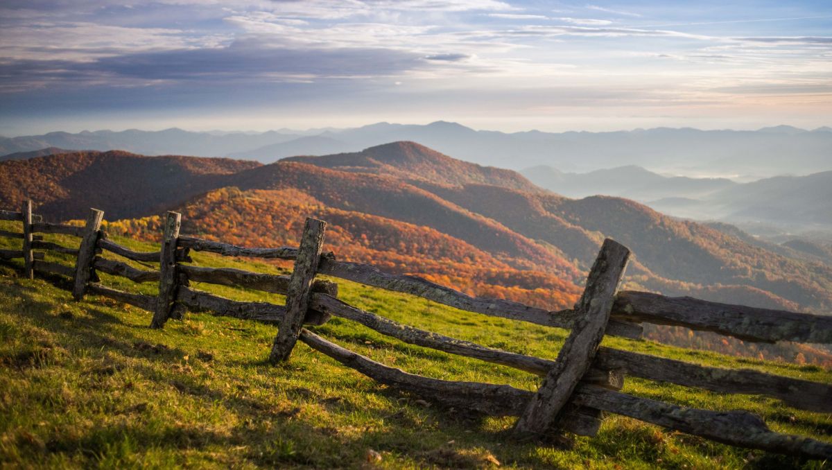 Wood fence with fall foliage and mountains in background at Cataloochee Ranch