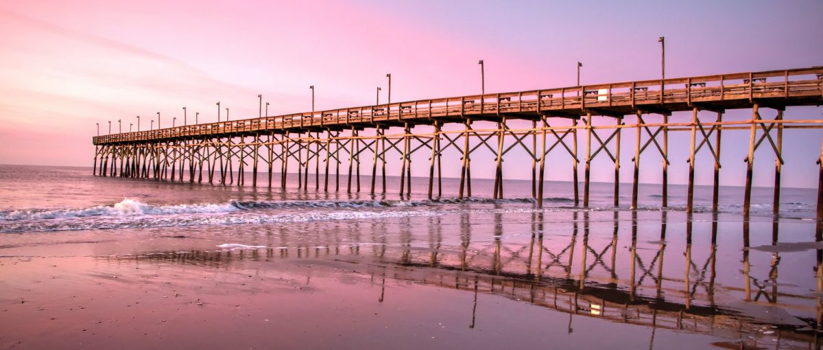 Sunset Beach Pier jutting out into the ocean with pink and purple sky in background