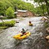 Rafters in river at Nantahala Outdoor Center with outpost and trees in background 