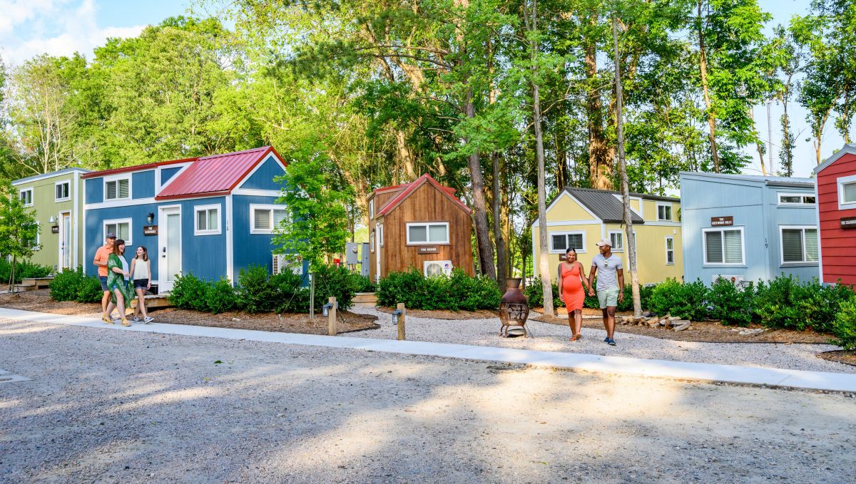 Family and couple walking outside tiny homes in River and Twine, a tiny house hotel, on sunny day
