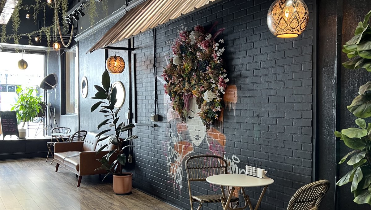 Interior of restaurant with black brick wall, flower art mural and table, chairs and couch