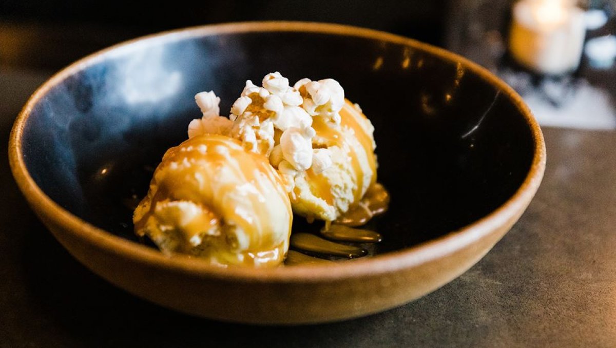 Ice cream with caramel and popcorn on top in bowl on table