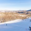 Aerial of snowy ski slopes and snowy mountains in background