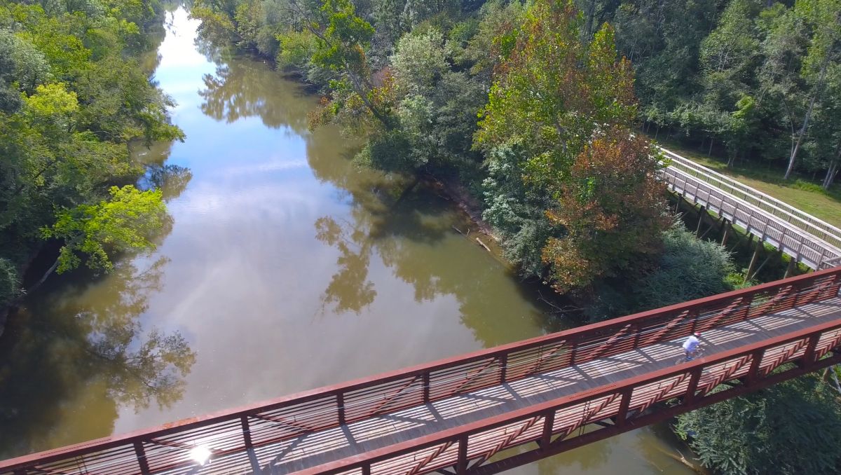 Aerial view of Clayton River Walk with person biking over pedestrian bridge during daytime
