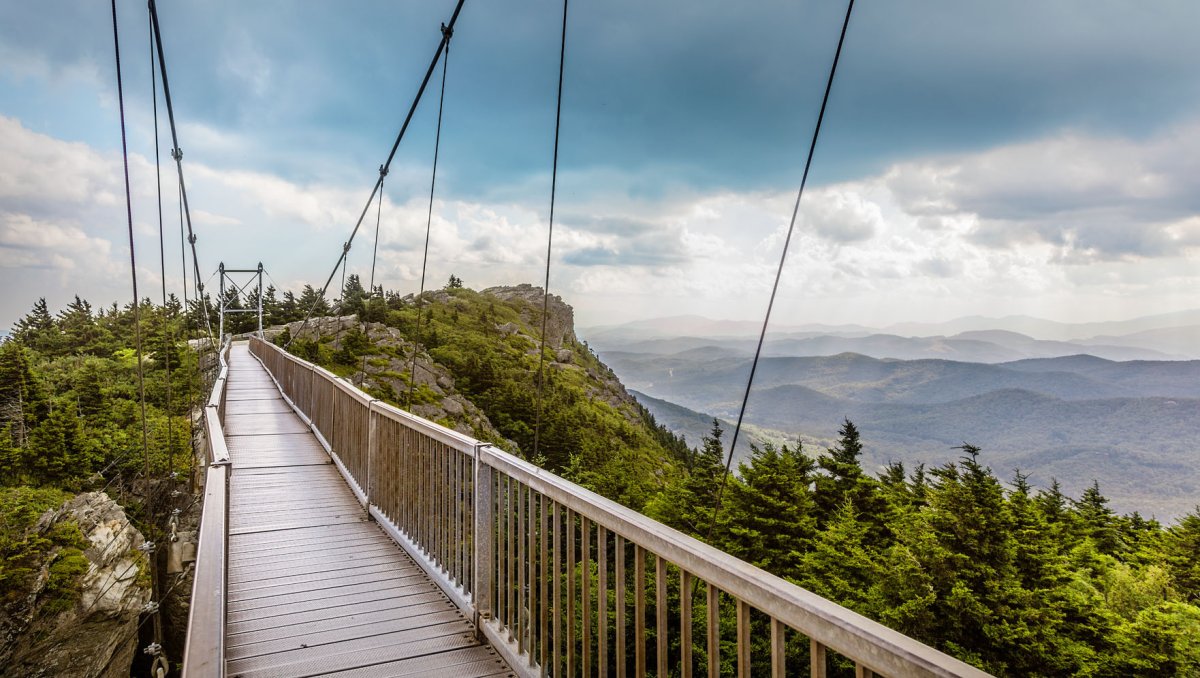 Entrance of Mile High Swinging Bridge with mountains in background during daytime