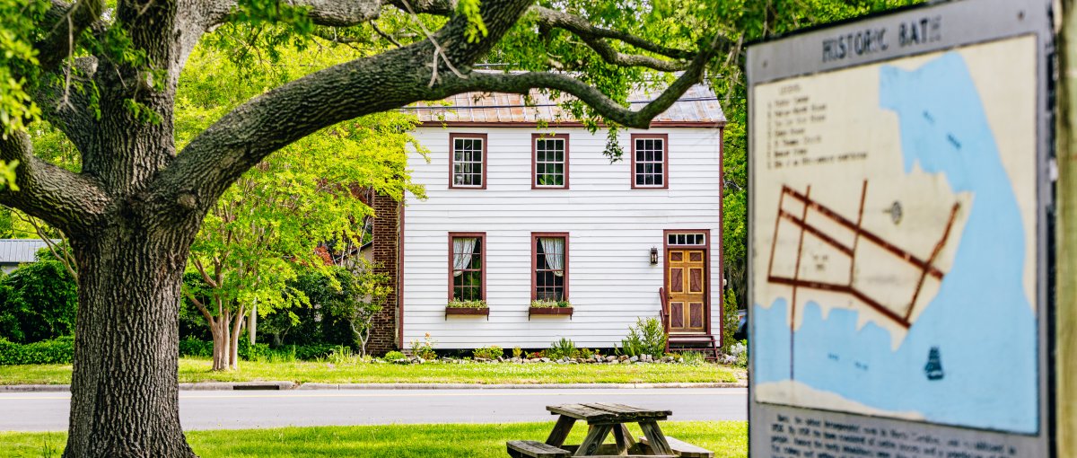 A scenic with a historic home in background and historic marker in foreground.