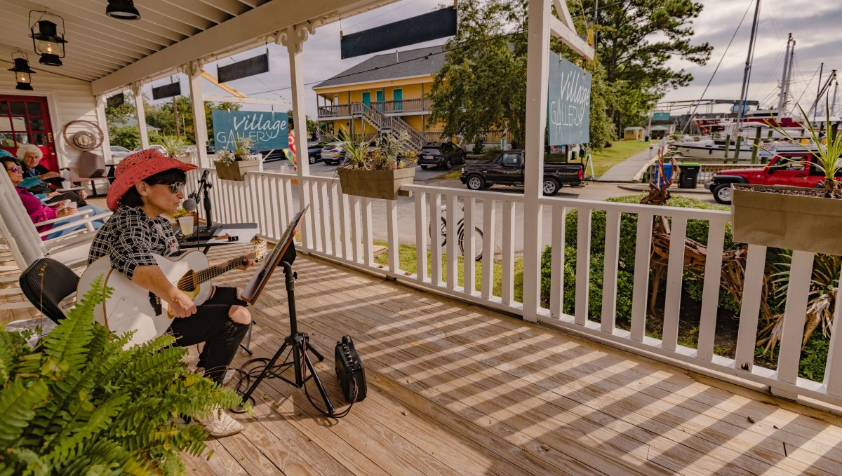 Musician playing guitar on porch of Ol' Front Porch Music Festival