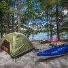 Campsite with a tent, kayak and chair beside Lake James with trees in background during daytime