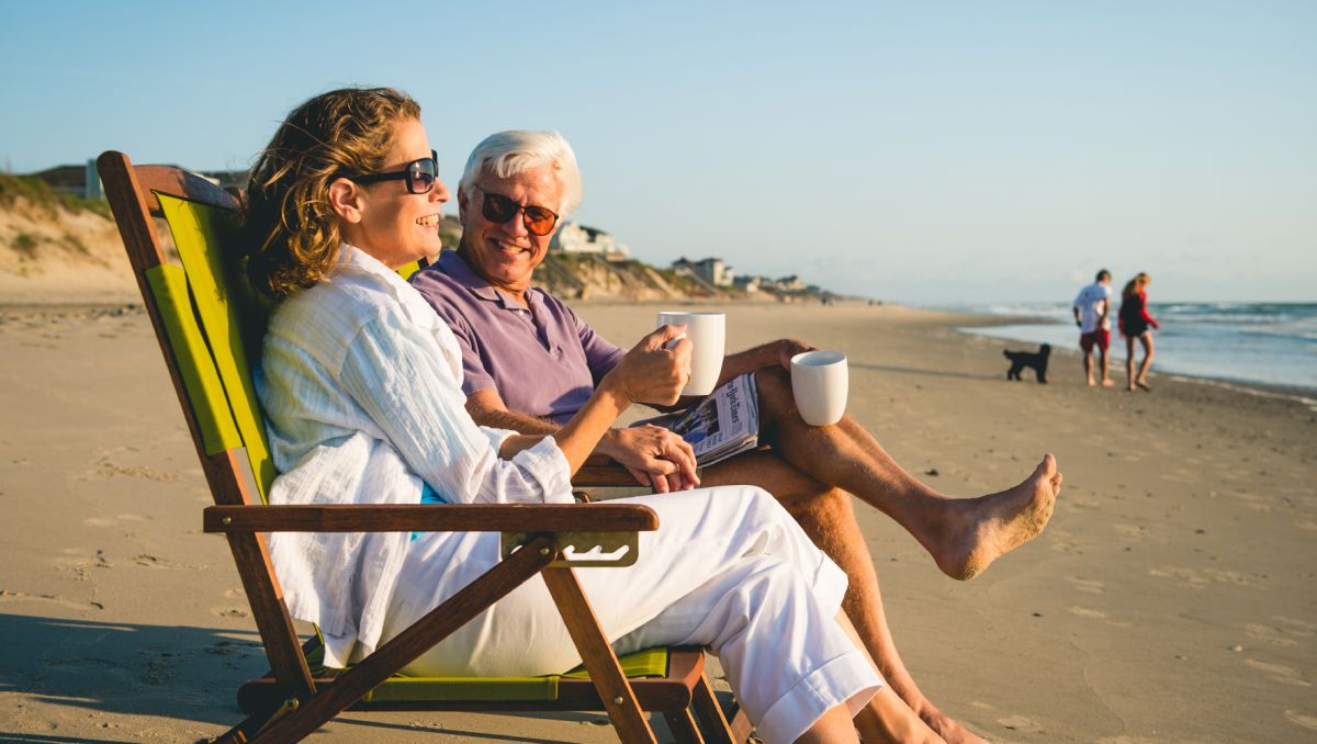 Man and woman drinking coffee on beach chairs looking out into ocean