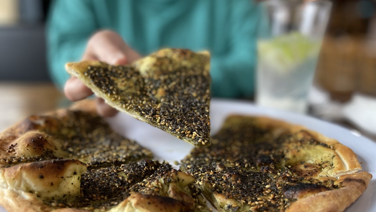 Person grabbing slice of pita from plate