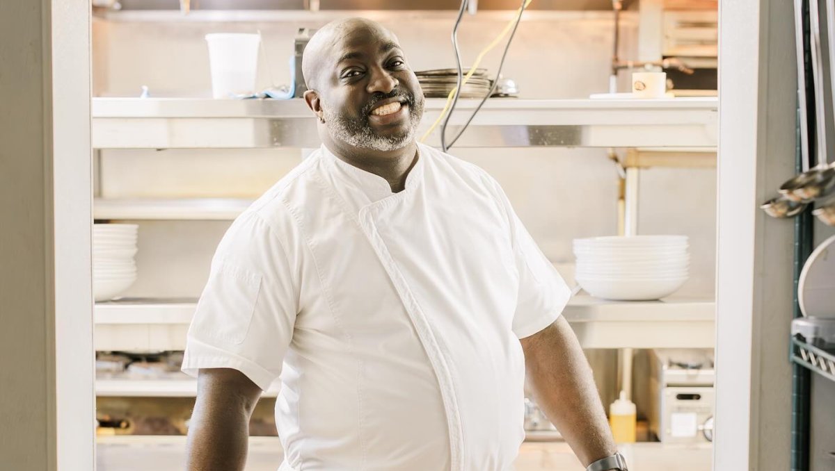 Chef standing in doorway of kitchen smiling.