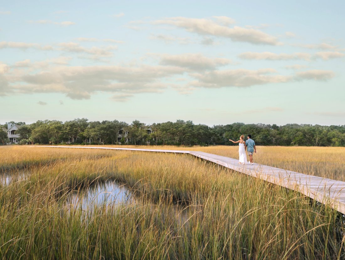 Couple walking on wood board throughout marsh