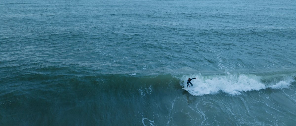 Aerial of man surfing in ocean with long-range ocean views