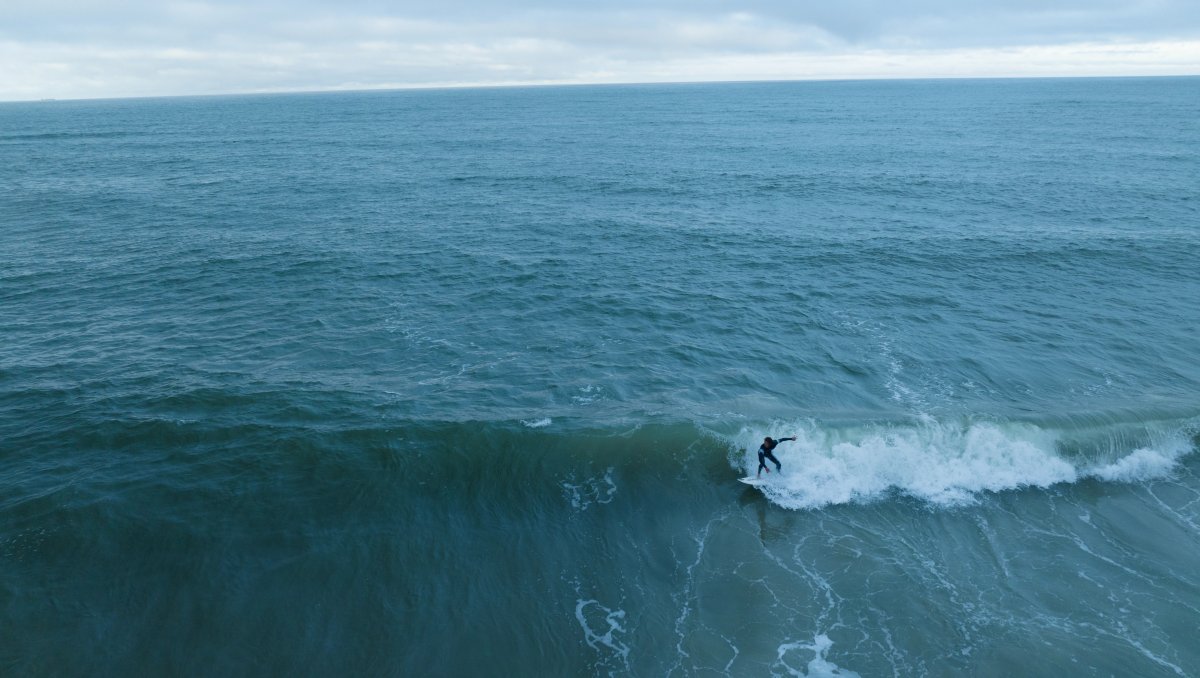 Aerial of man surfing in ocean with long-range ocean views