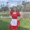 Young woman dressed in Scottish dance clothing posing in front of pond.