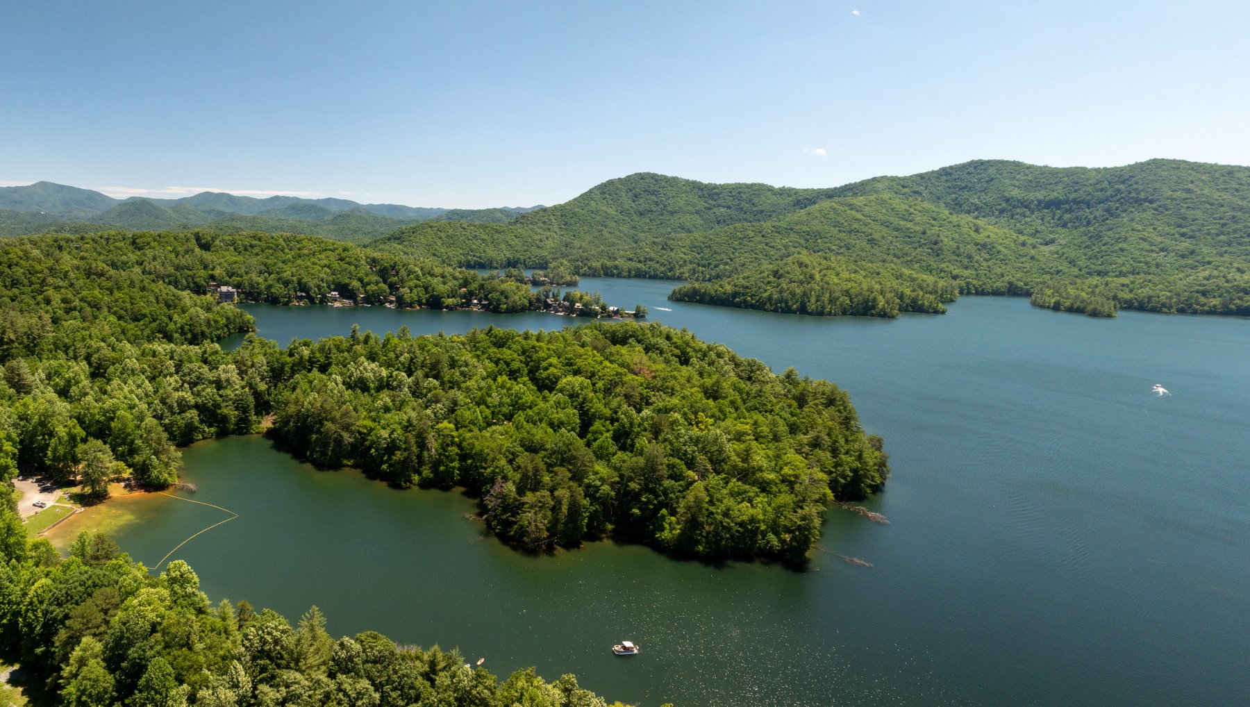 Aerial of Lake Santeetlah with boats in water surrounded by rolling hills and mountains in summer.