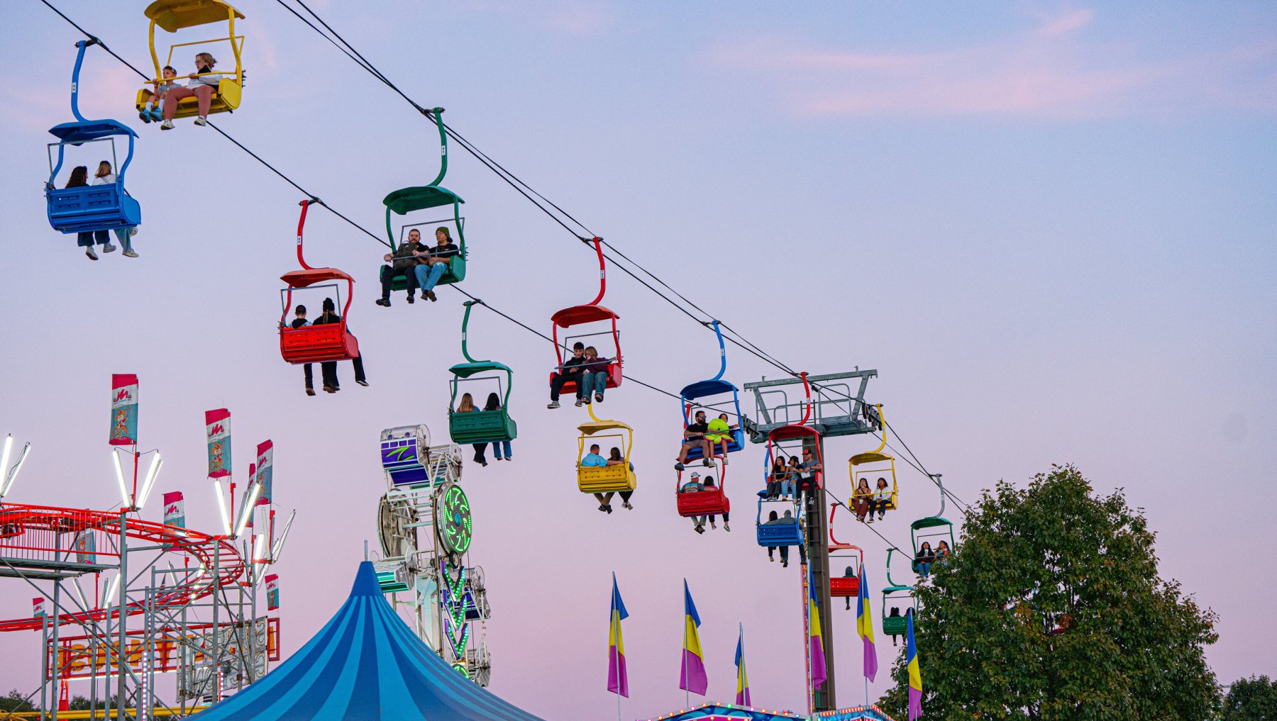 People riding colorful state fair gondolas over food vendors.