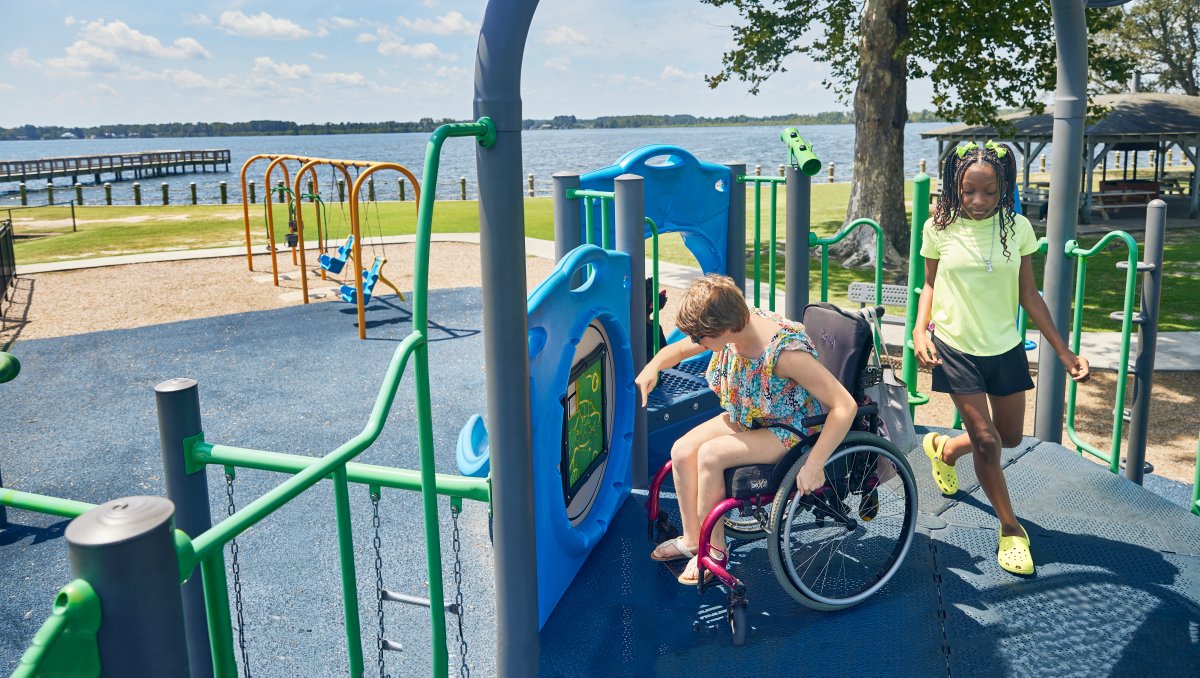 Two children, one in a wheelchair, playing on playground.