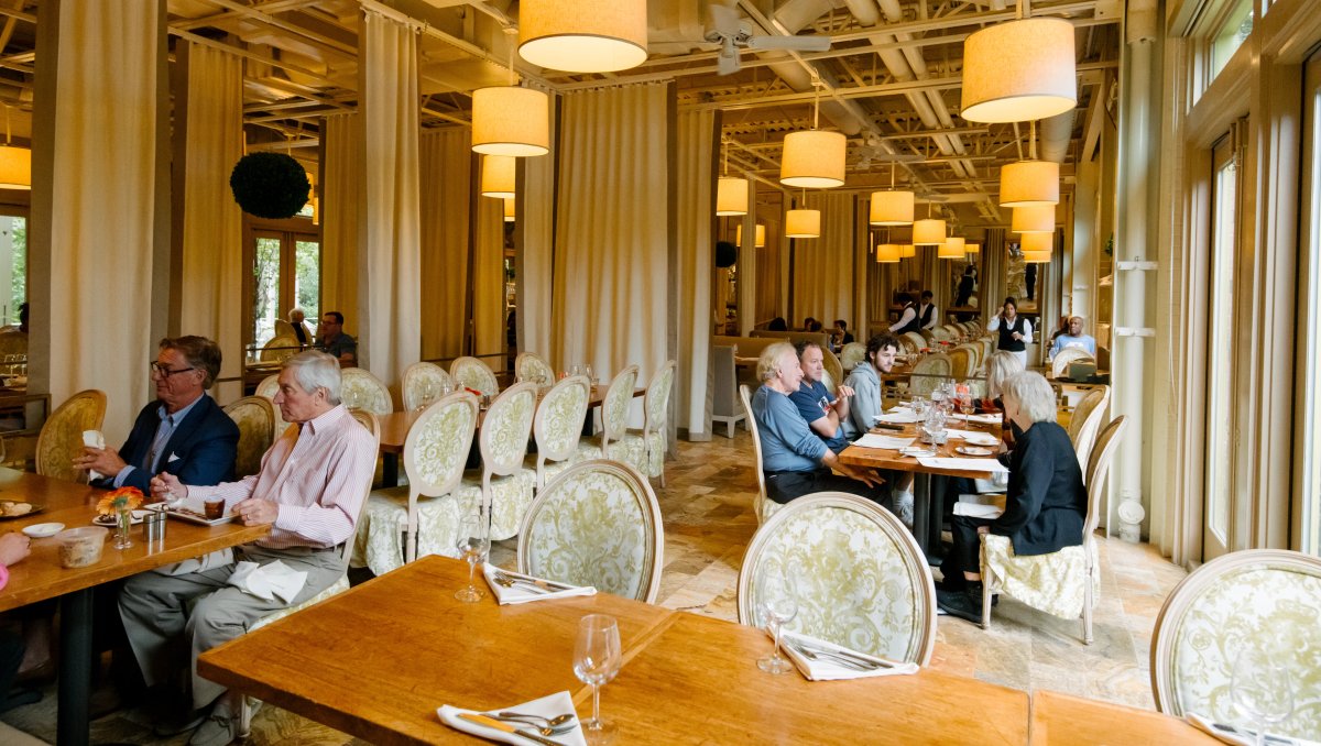 Two tables of people enjoying meals indoors in bright and airy restaurant