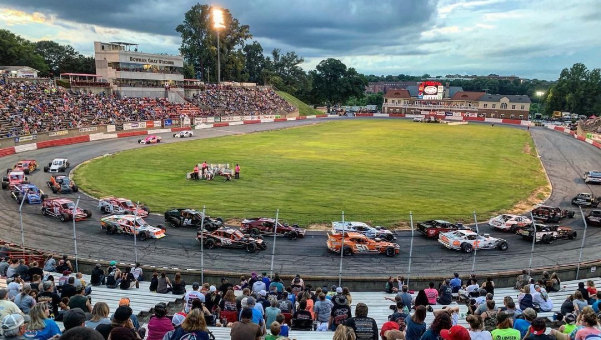 Crowd of fans watching cars race around Bowman Gray Stadium's racetrack
