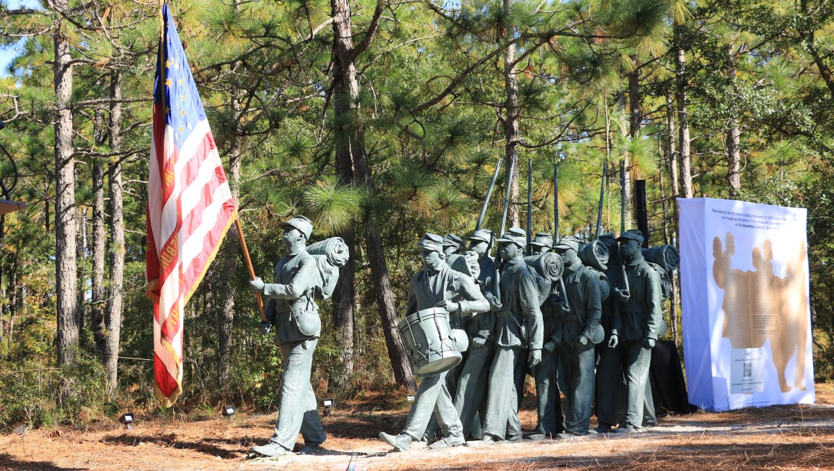 Lifesize statue of men in United States Colored Troops, outside with trees in background