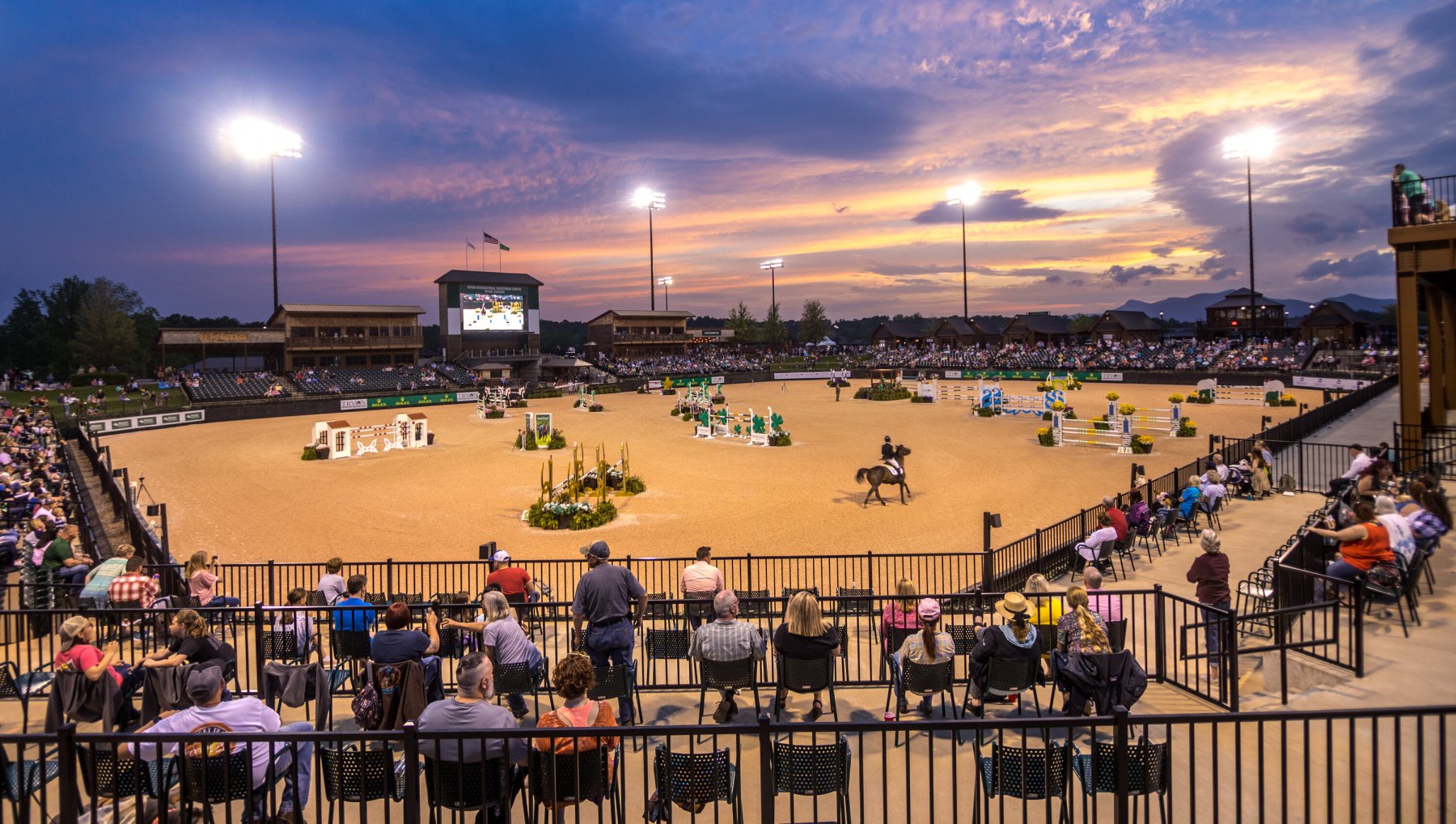 Saturday Night Lights at Tryon International Equestrian Center as horses perform under sunset.