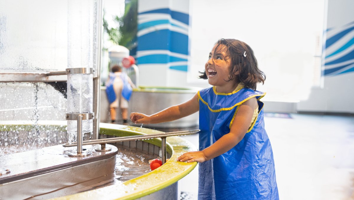 Child playing with water exhibit at children's museum.