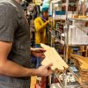 Man holding North Carolina-shaped cutting board in gift shop with woman looking at shelves of items in background