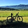 Bike leaned up against fence with fields, trees and mountains in background