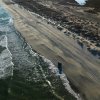 Aerial of Jeep driving on beach parallel to ocean
