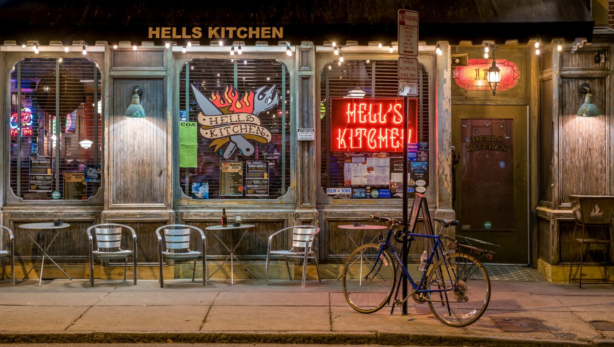 Exterior of Hell's Kitchen restaurant with decal and bright signs in windows