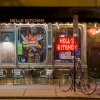 Exterior of Hell's Kitchen restaurant with decal and bright signs in windows