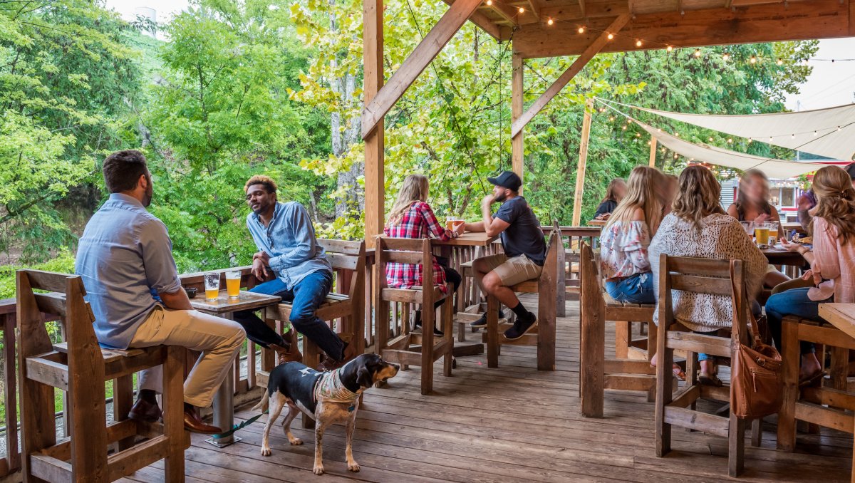 People enjoying beers on brewery outdoor patio during daytime.