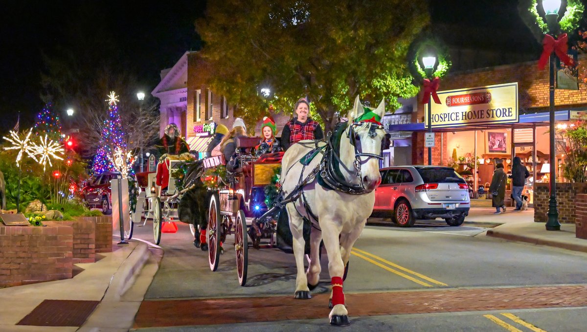 Horsedrawn carriage pulling people through charming downtown decorated for Christmas. 