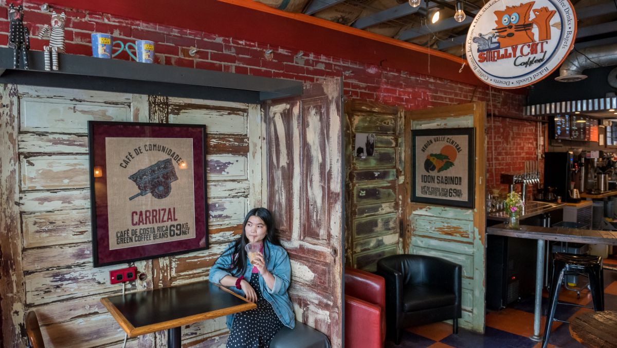 Woman sipping ice coffee while sitting in booth in coffee shop